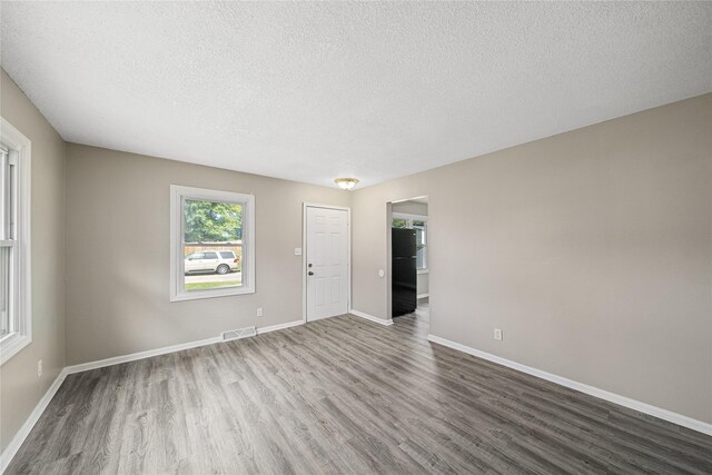interior space featuring wood finished floors, a textured ceiling, baseboards, and visible vents
