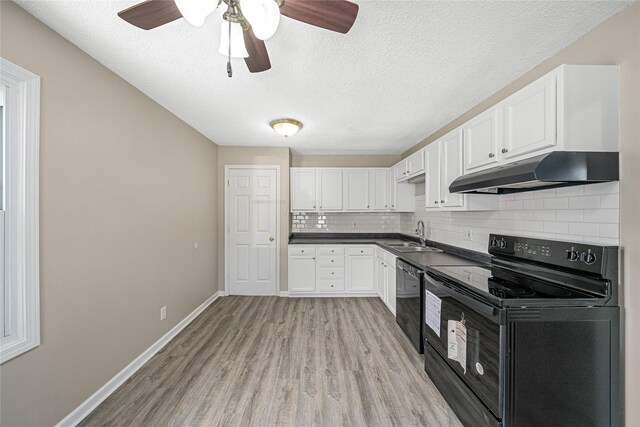 kitchen with a sink, under cabinet range hood, dark countertops, black appliances, and decorative backsplash