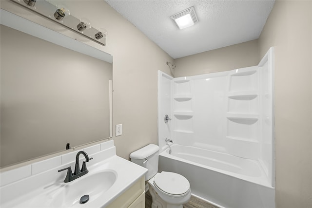 full bathroom featuring a textured ceiling, shower / washtub combination, vanity, and toilet