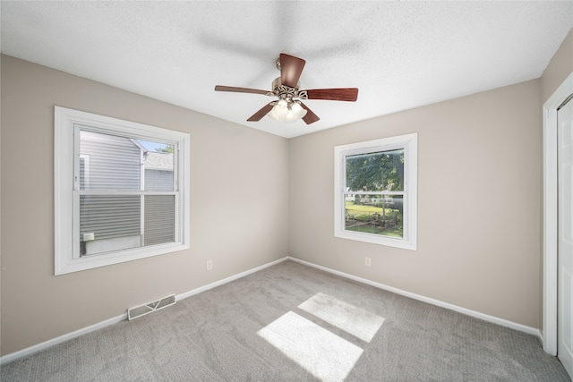 empty room with light carpet, ceiling fan, and plenty of natural light