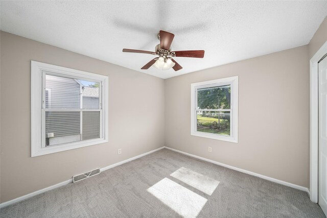 unfurnished bedroom with carpet flooring, a textured ceiling, baseboards, and visible vents