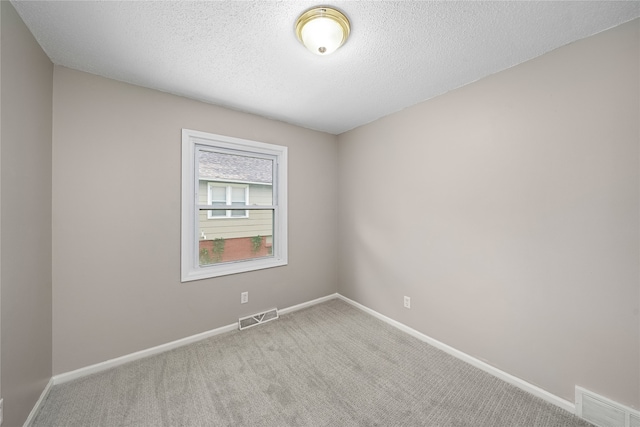 unfurnished room with a textured ceiling and light colored carpet