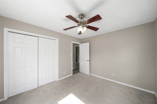 unfurnished bedroom featuring ceiling fan, light colored carpet, and a closet