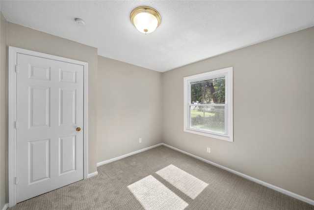 empty room with a textured ceiling and light carpet