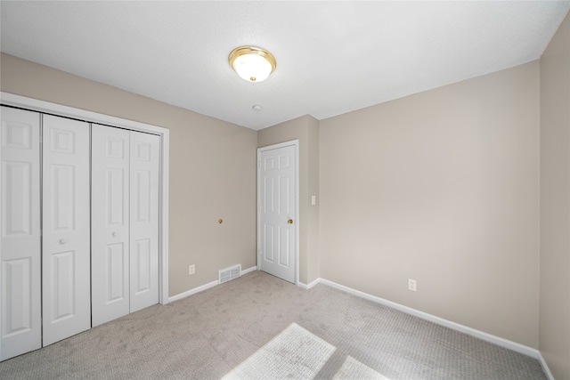 unfurnished bedroom featuring a closet and light colored carpet