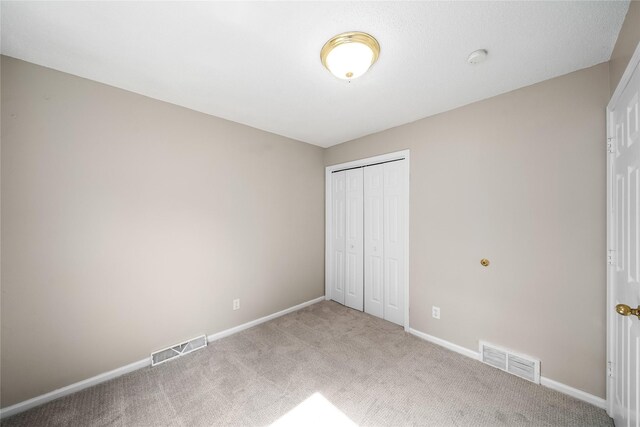 unfurnished bedroom with carpet floors, baseboards, a closet, and visible vents