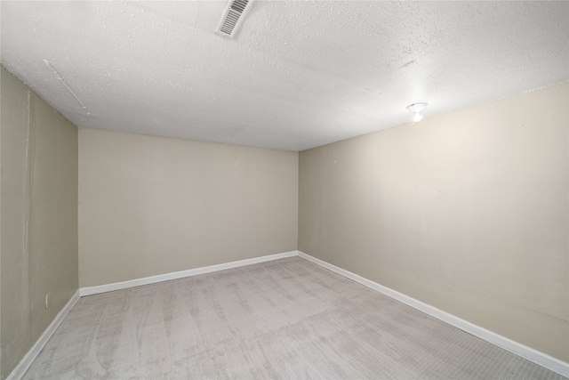 spare room featuring light colored carpet and a textured ceiling