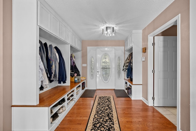 mudroom with light wood-type flooring and a textured ceiling