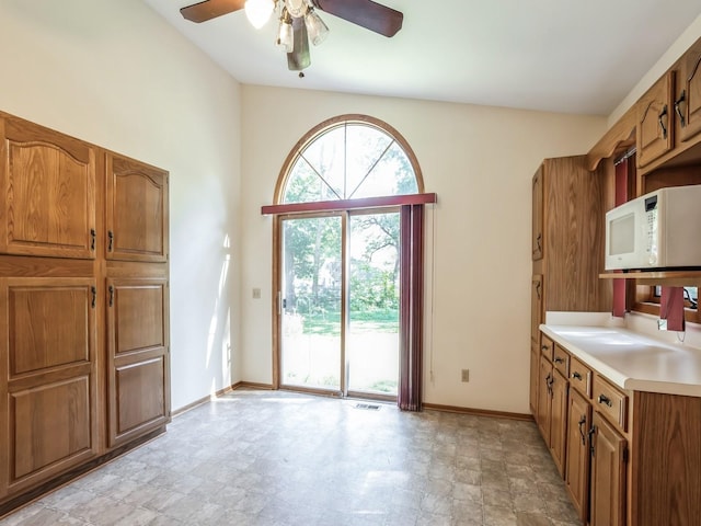 655 64th St, Des Moines, IA 50312 - interior space with baseboards, white microwave, light countertops, a ceiling fan, and brown cabinets