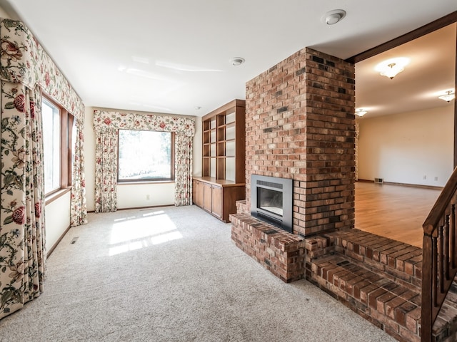 unfurnished living room with a brick fireplace and light colored carpet