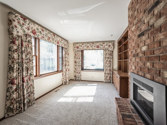 unfurnished living room featuring light carpet, heating unit, a brick fireplace, and built in shelves