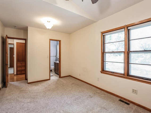 interior space with connected bathroom, ceiling fan, and light colored carpet