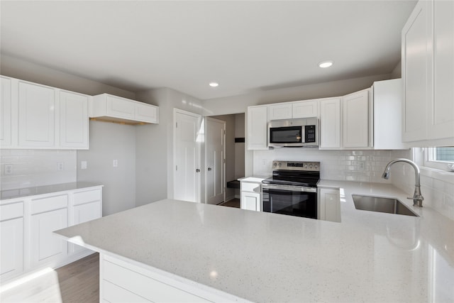 kitchen with sink, white cabinetry, stainless steel appliances, and tasteful backsplash