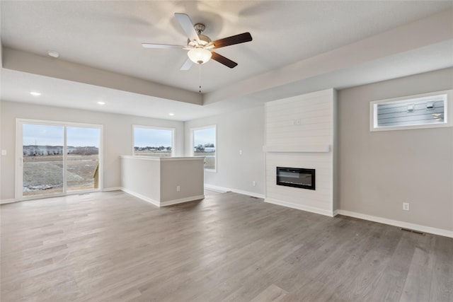 unfurnished living room featuring hardwood / wood-style flooring, a fireplace, and ceiling fan