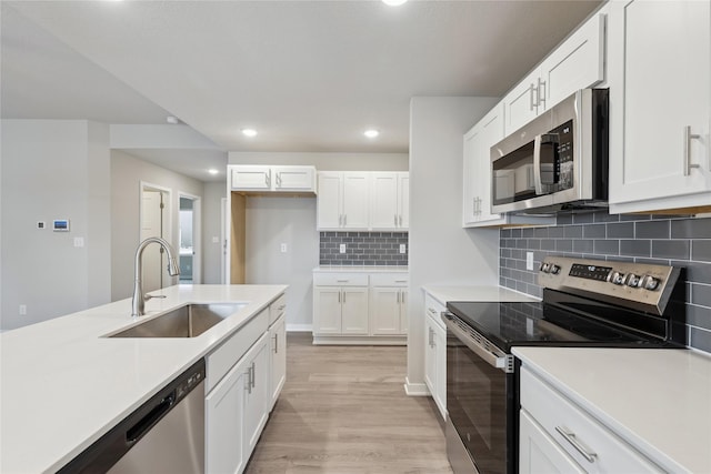 kitchen with white cabinetry, appliances with stainless steel finishes, sink, and light hardwood / wood-style flooring