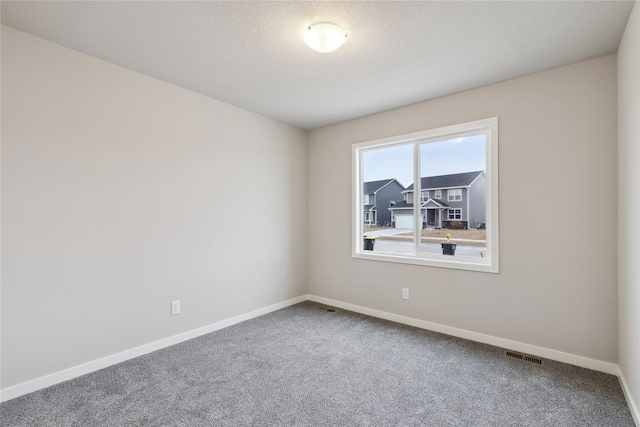 carpeted empty room featuring a textured ceiling