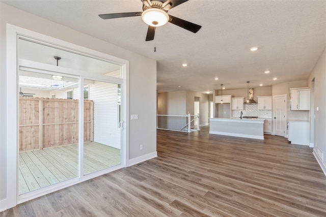 unfurnished living room featuring a textured ceiling, hardwood / wood-style flooring, and ceiling fan