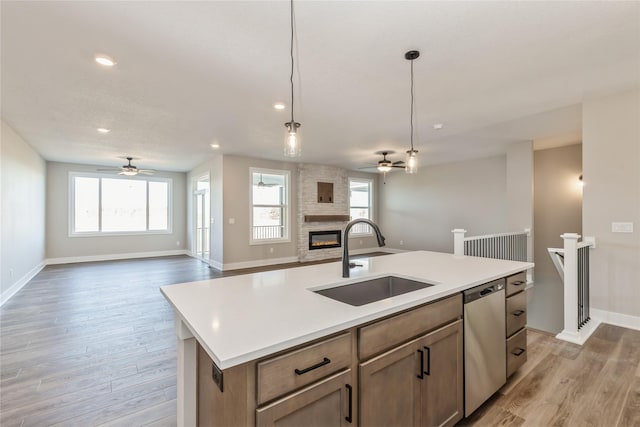 kitchen with dishwasher, sink, ceiling fan, an island with sink, and decorative light fixtures