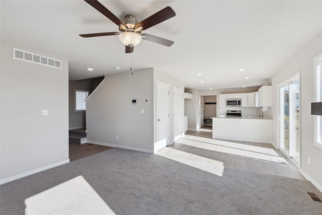 unfurnished living room featuring light carpet and sink