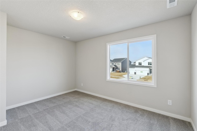 carpeted empty room with a textured ceiling