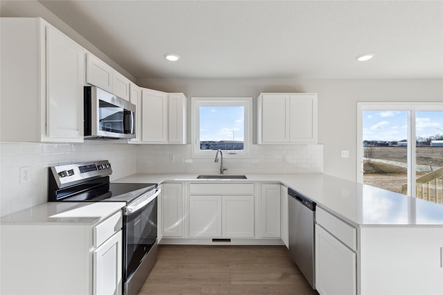 kitchen with white cabinets, appliances with stainless steel finishes, sink, and light hardwood / wood-style flooring