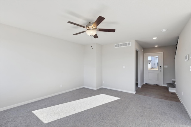 empty room with ceiling fan and dark carpet