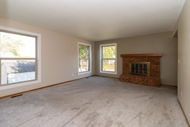 unfurnished living room with baseboards, visible vents, carpet floors, a textured ceiling, and a brick fireplace