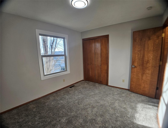 unfurnished bedroom featuring visible vents, baseboards, carpet, and a closet