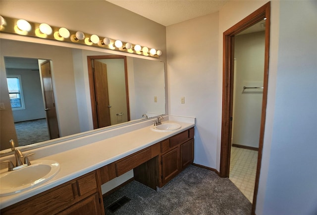 full bathroom with a sink, visible vents, baseboards, and double vanity