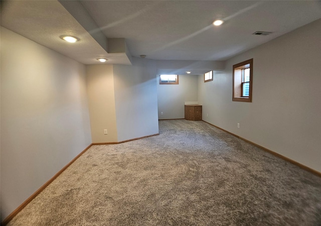 below grade area featuring visible vents, baseboards, and carpet