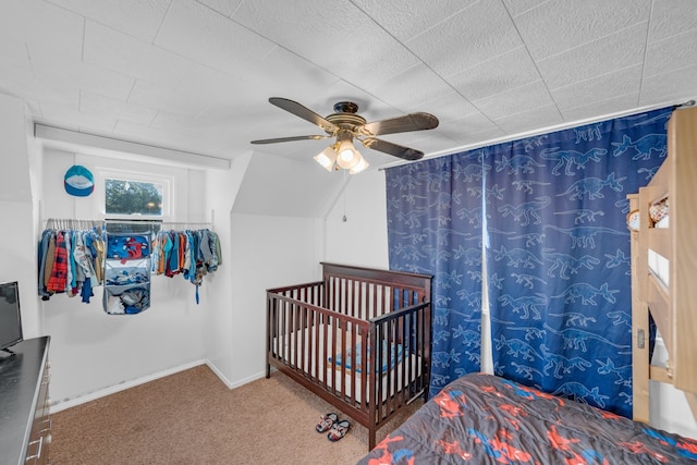 carpeted bedroom featuring ceiling fan and a nursery area