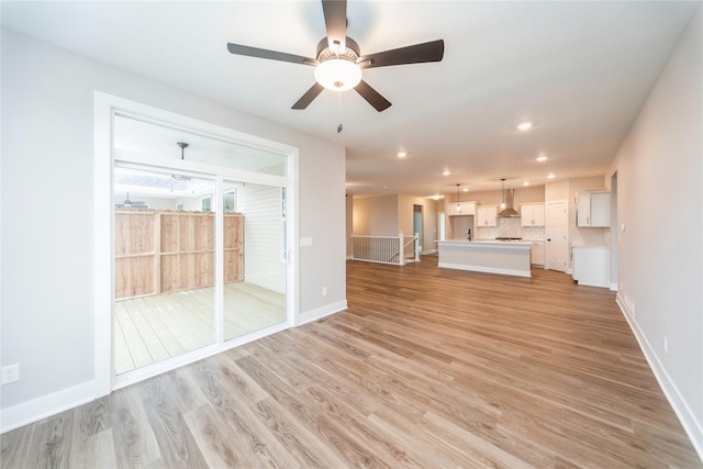 unfurnished living room featuring ceiling fan and light hardwood / wood-style flooring