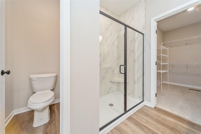 bathroom with hardwood / wood-style flooring, toilet, and an enclosed shower