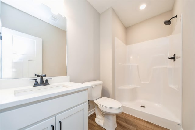 bathroom with hardwood / wood-style flooring, a shower, toilet, and vanity