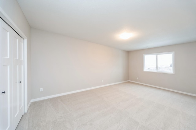 unfurnished bedroom featuring light colored carpet and a closet