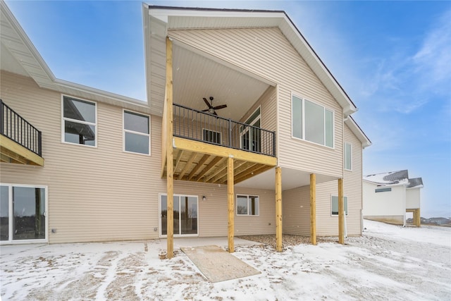 snow covered house featuring ceiling fan and a balcony