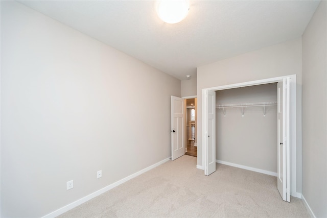 unfurnished bedroom featuring light colored carpet and a closet