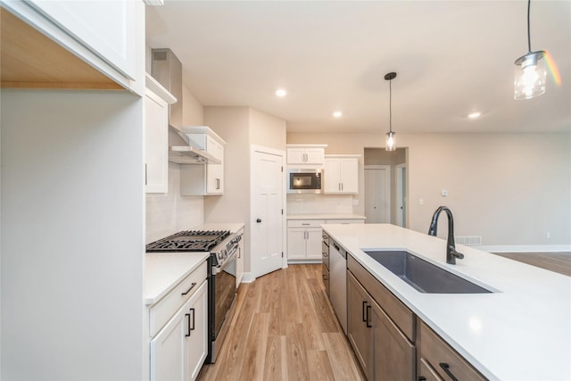 kitchen with pendant lighting, appliances with stainless steel finishes, sink, white cabinetry, and decorative backsplash