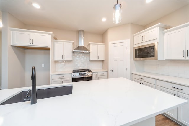 kitchen featuring stainless steel gas stove, built in microwave, hanging light fixtures, wall chimney exhaust hood, and backsplash