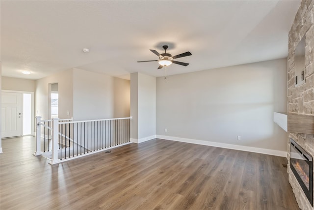 unfurnished room with a fireplace, dark hardwood / wood-style floors, and ceiling fan