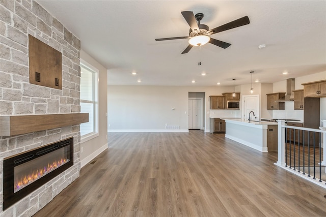 unfurnished living room with a fireplace, dark hardwood / wood-style floors, ceiling fan, and sink