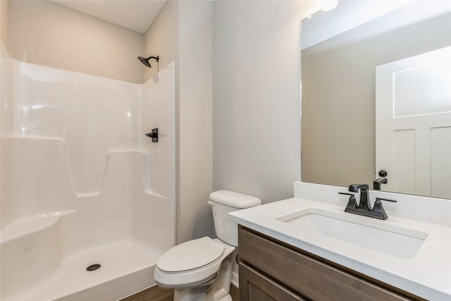 bathroom with a shower, vanity, wood-type flooring, and toilet