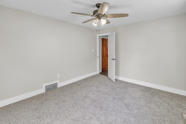 carpeted empty room featuring baseboards, visible vents, and a ceiling fan