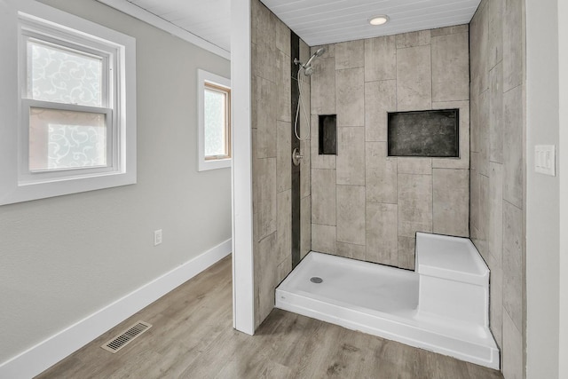 full bathroom with visible vents, a tile shower, baseboards, and wood finished floors