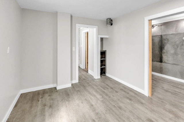 spare room with baseboards and wood finished floors