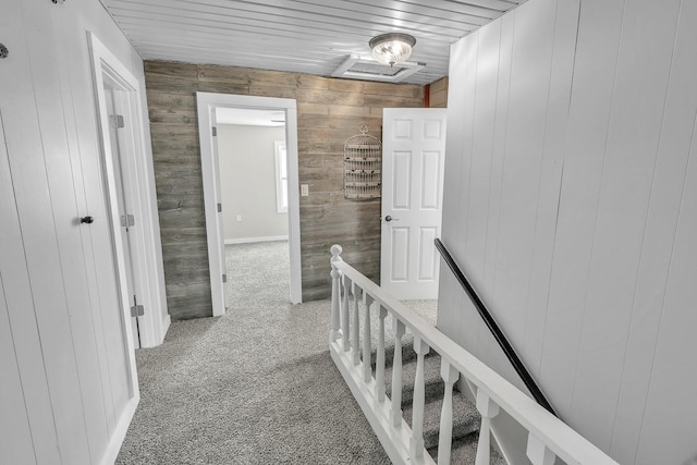 hallway featuring wood ceiling, carpet flooring, and an upstairs landing