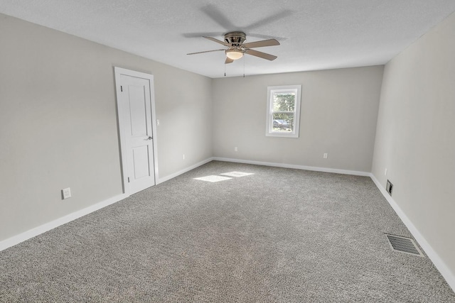 unfurnished room with a textured ceiling, carpet floors, ceiling fan, and visible vents