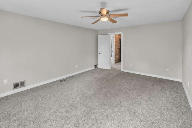 carpeted spare room featuring baseboards, visible vents, and ceiling fan