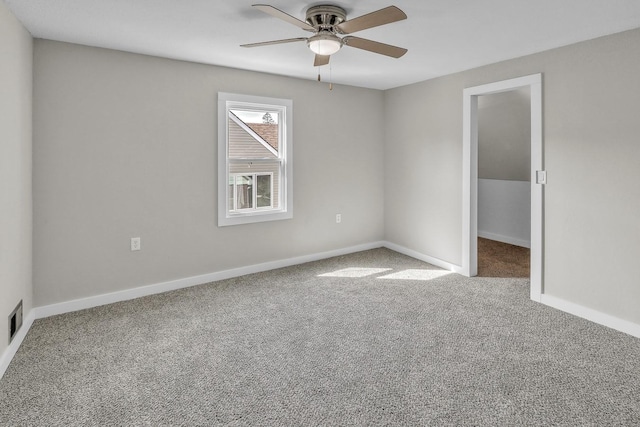 carpeted empty room featuring visible vents, a ceiling fan, and baseboards