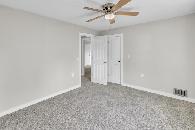 carpeted spare room featuring ceiling fan, visible vents, and baseboards